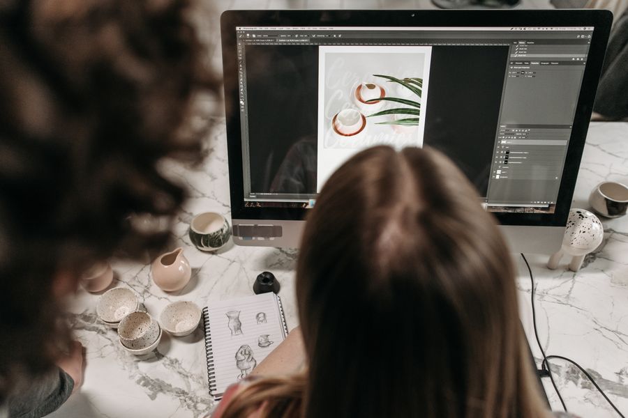 Two people collaborate on photo editing using Adobe Photoshop in a studio setting.