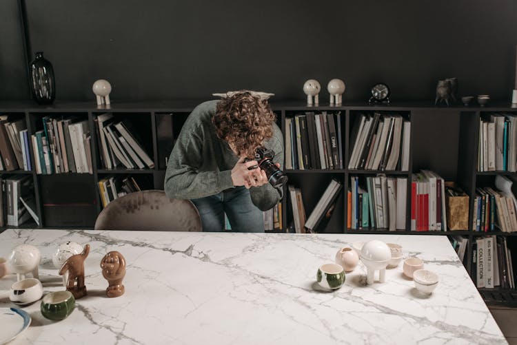 Man Taking Picture Of Ceramic Products On Table