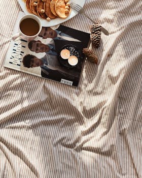Delicious homemade pancakes and coffee on a bed create a cozy morning vibe.