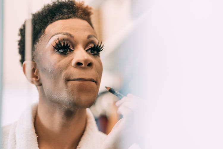 Black Man Applying Lip Pencil Near Mirror