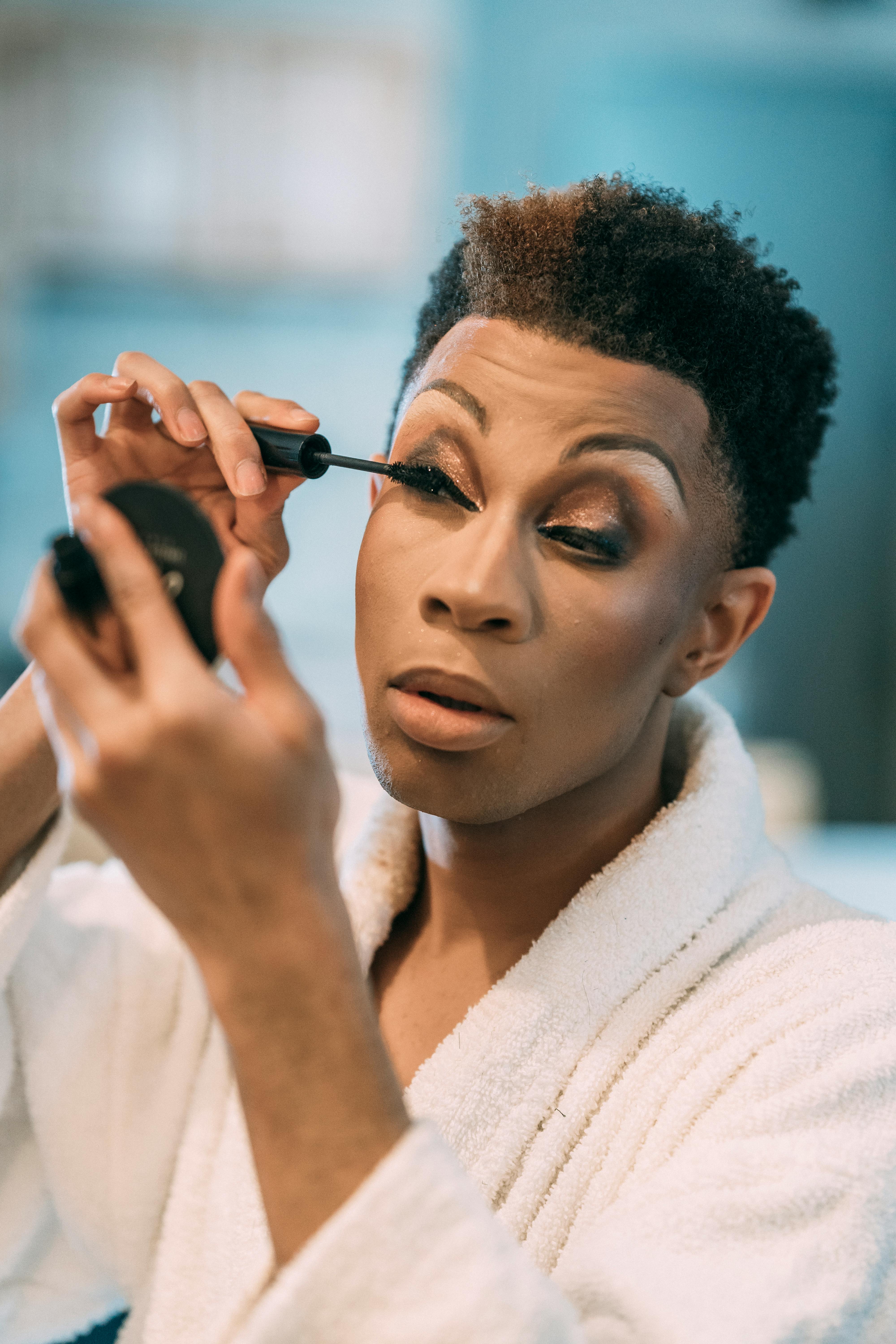 feminine black man applying makeup