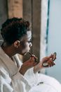 Eccentric black man with mirror doing makeup