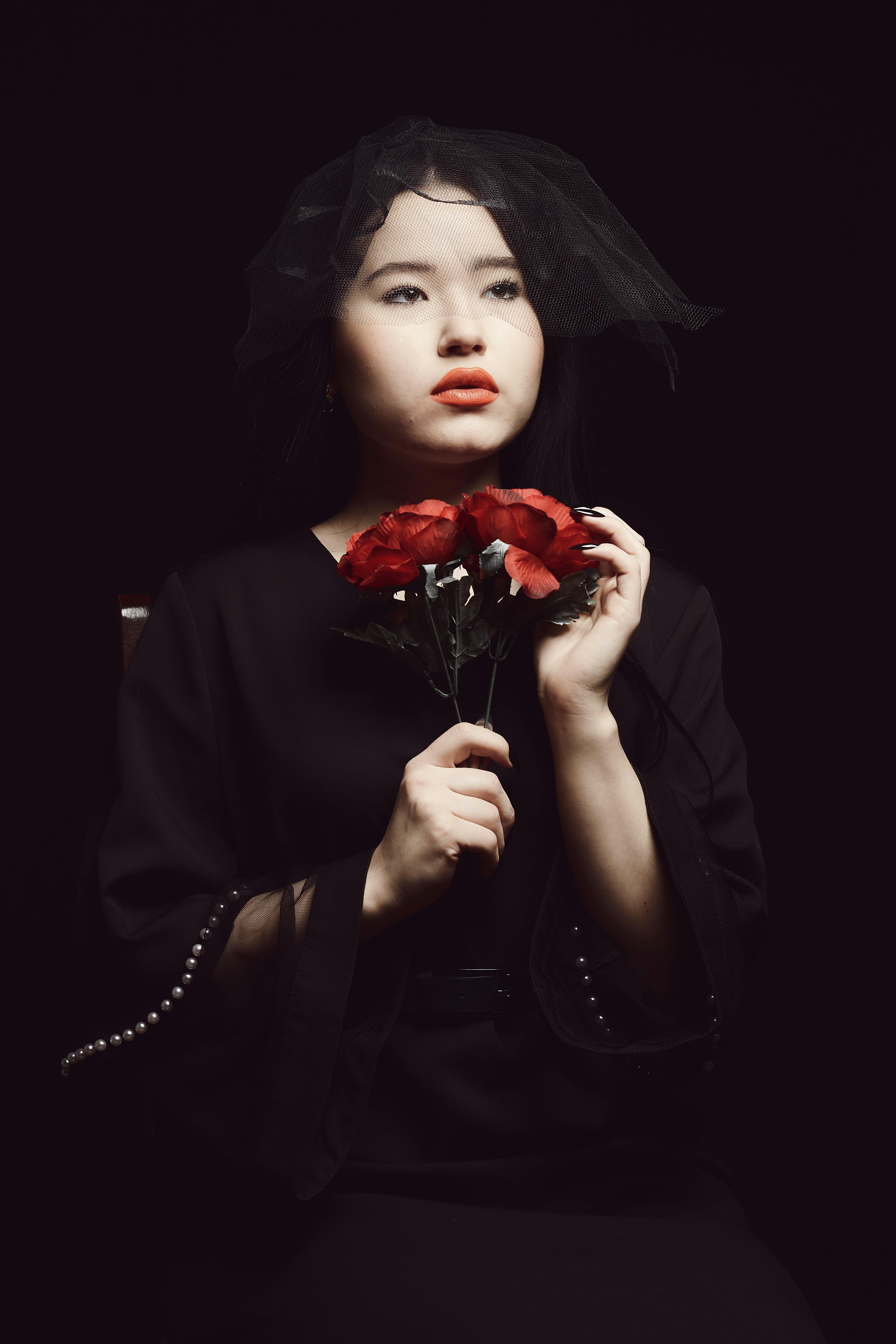 girl wearing black clothes while holding red roses
