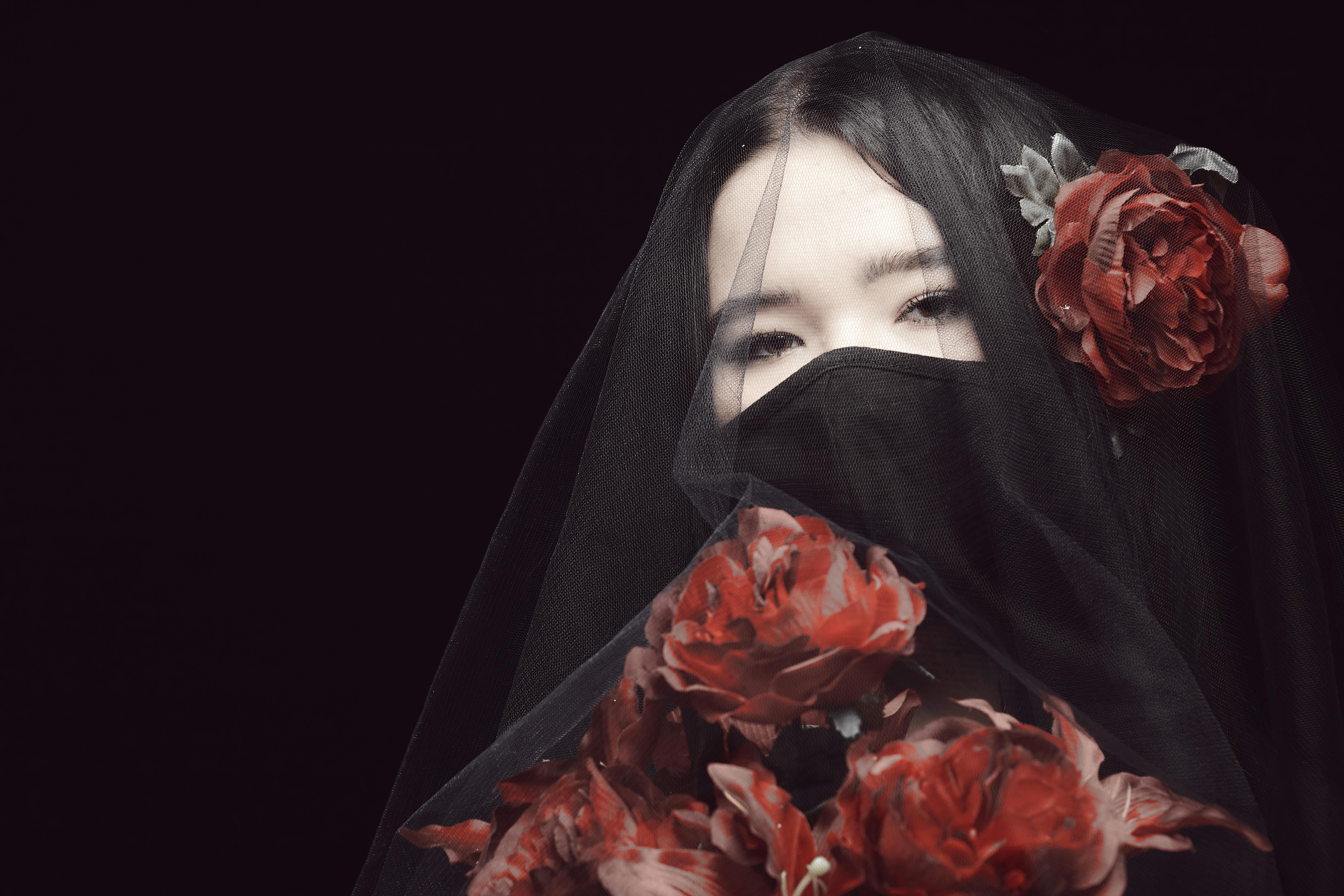 woman in black hijab with red rose petals