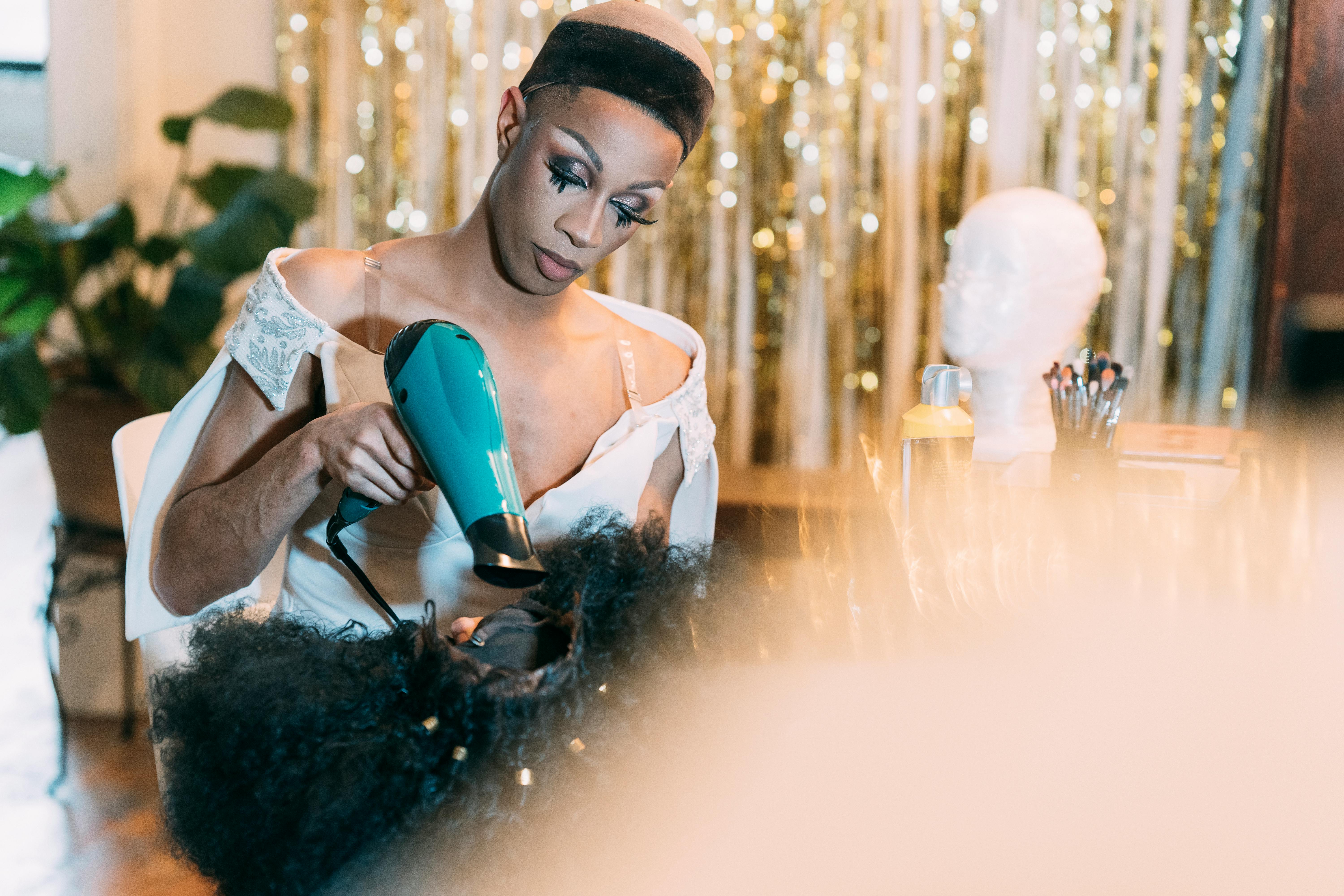 drag queen in dress drying wig