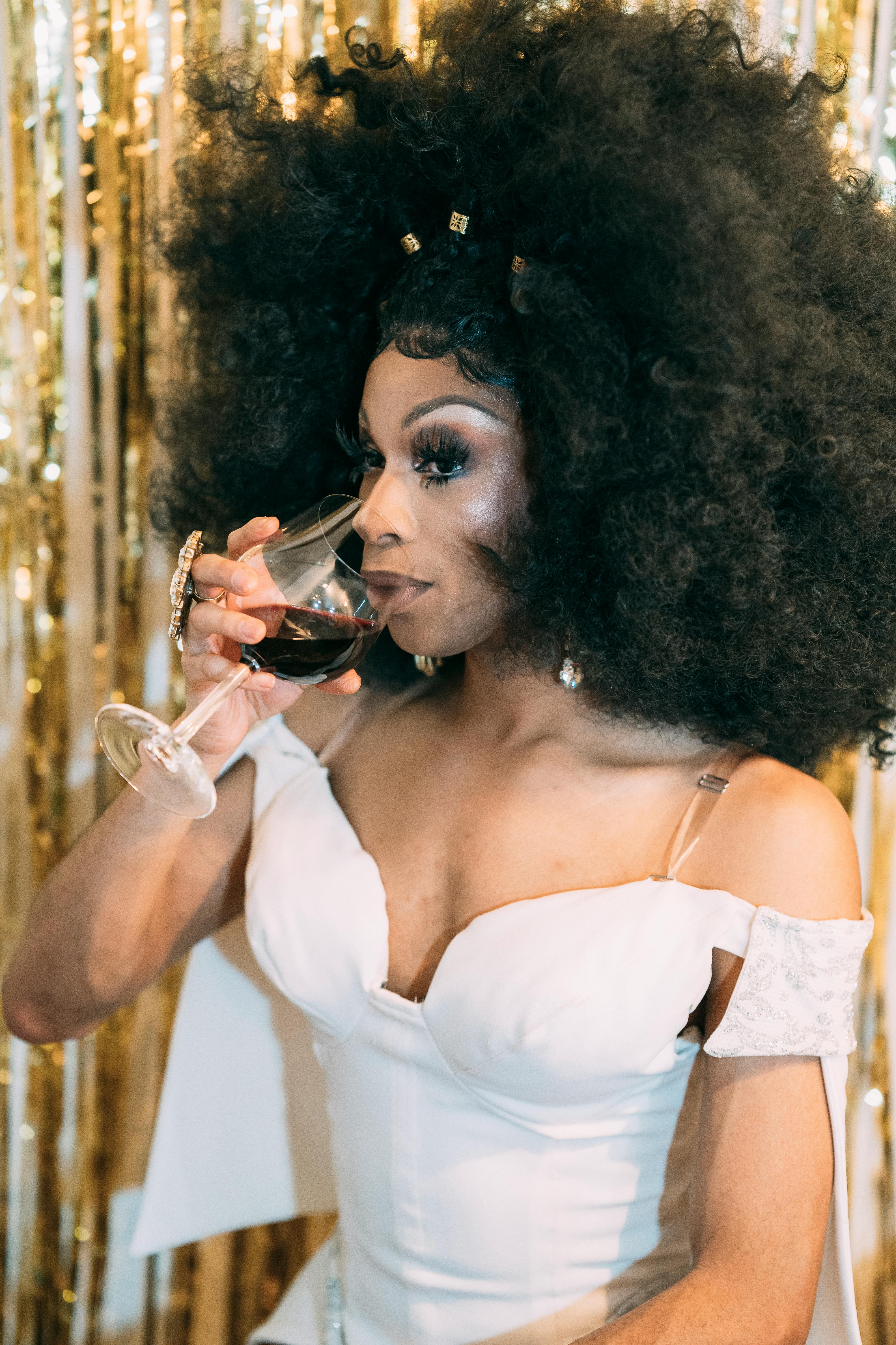 drag queen in wig drinking wine