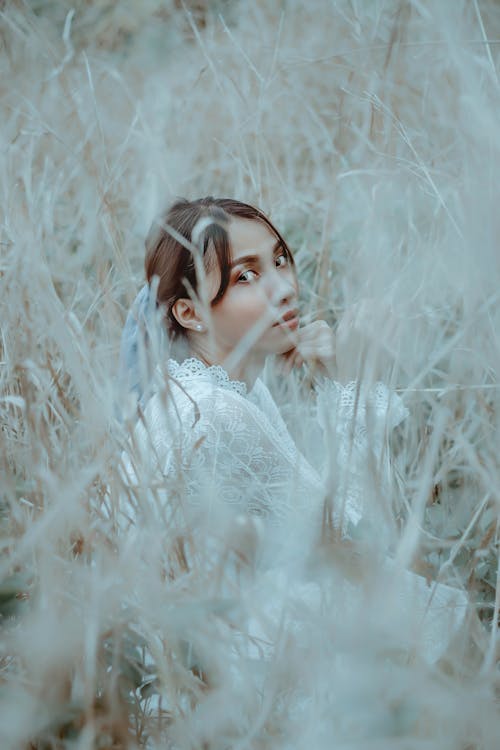 Free Calm young ethnic lady resting in grassy field in countryside Stock Photo