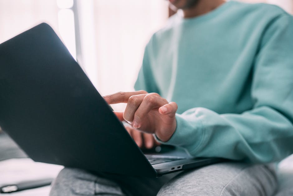 A man using a laptop indoors, working in a casual home setting.