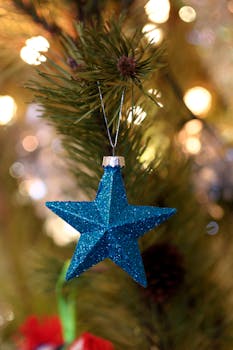 特写：圣诞树枝上悬挂的闪闪发光的蓝色星星装饰品