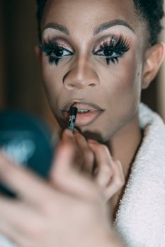 Man with bright makeup painting lips