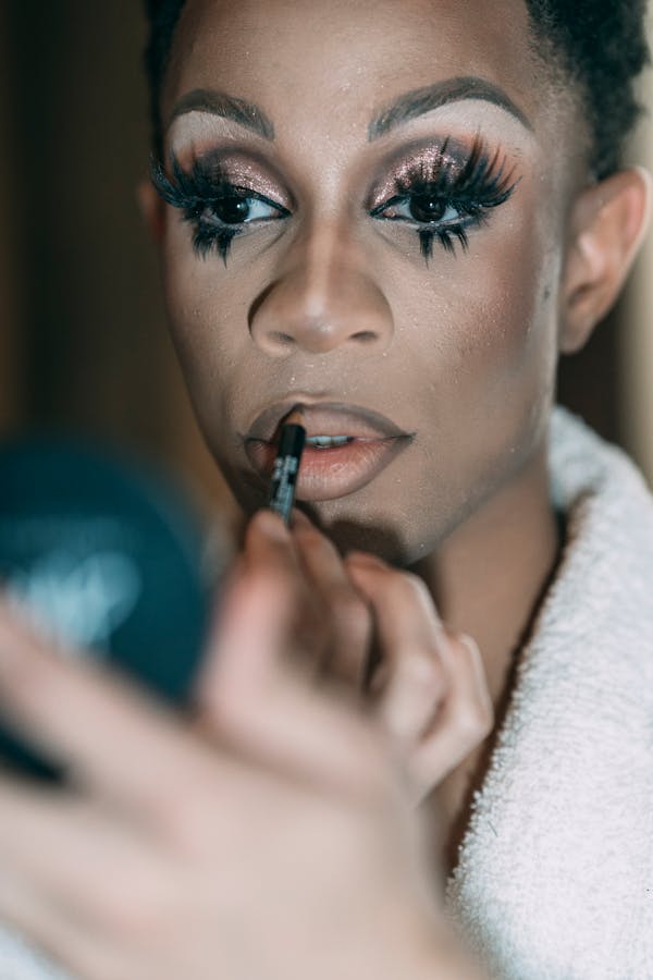 Man with bright makeup painting lips