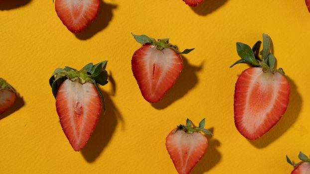 Slice of fresh strawberries on a bright yellow background showcasing vibrant color contrast.