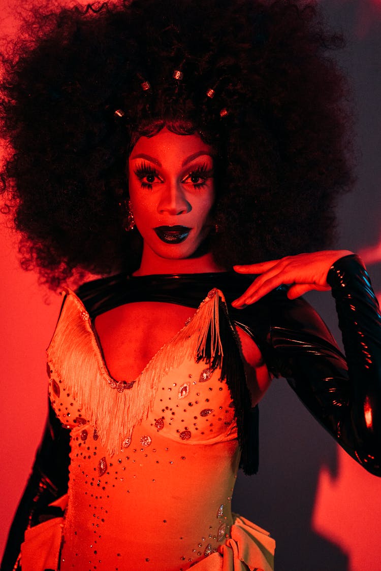 Extravagant Drag Queen Performer Standing In Room With Red Illumination