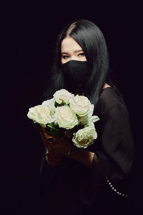 Free A Woman in Black Top Holding a Bouquet of White Flowers Stock Photo