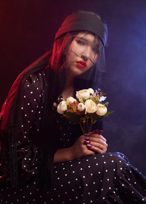 Free A Woman Wearing Black Dress and Veil Holding a Bunch of Flowers Stock Photo
