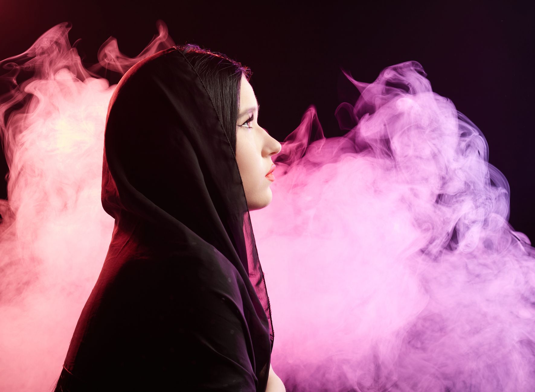 Artistic profile of a woman in a head scarf surrounded by colorful smoke