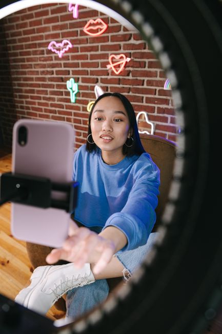 Content creator in studio with neon lights filming smartphone content
