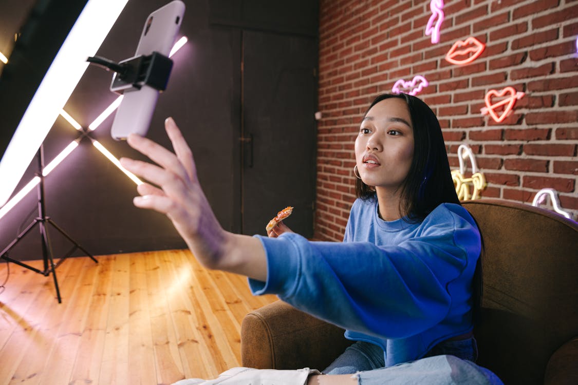 influencer marketing Free A Woman Using Her Phone while Attached on a Ring Light Stock Photo