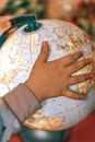 From above of crop little child exploring planet with miniature of Earth in hands while studying geography