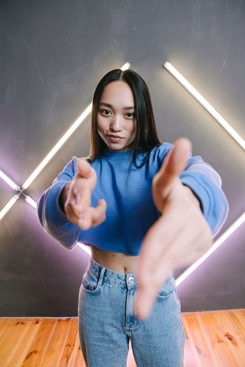Free Teenager in a stylish outfit poses with neon lights creating a vibrant, modern feel. Stock Photo
