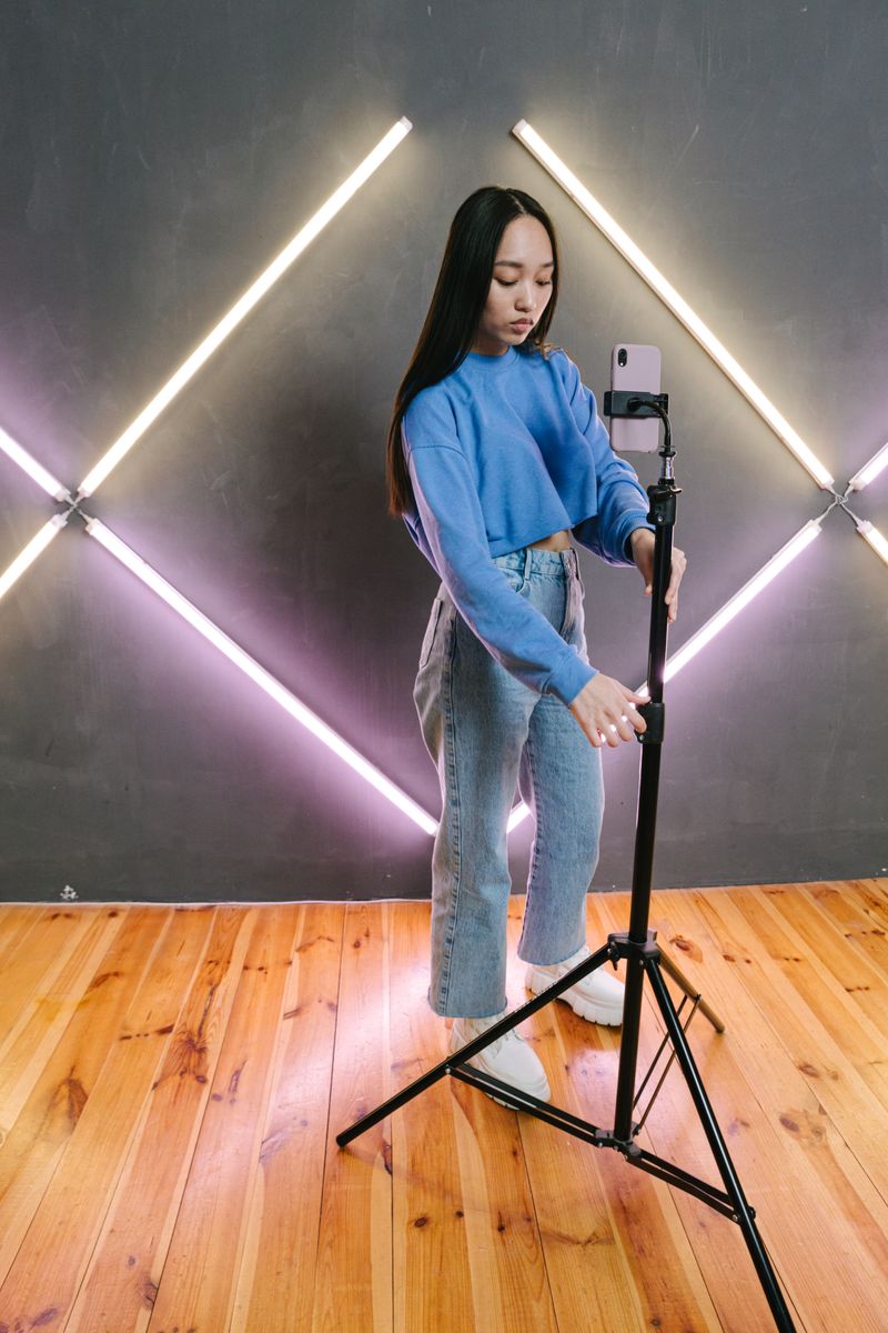 Content creator adjusting a smartphone mounted on a light stand
