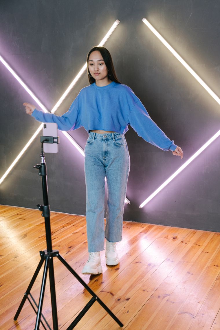 Creator filming a dance clip on a phone mounted to a tripod in a lit studio — photo by Ivan S on Pexels