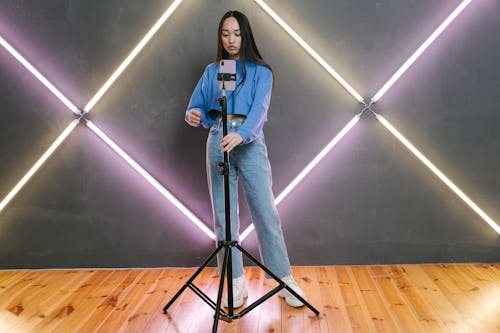 Woman in Blue Long Sleeve Shirt and Blue Denim Jeans Standing on Black Metal Stand