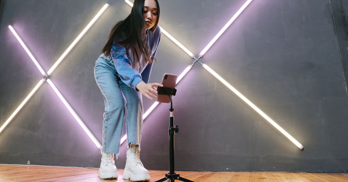Music studio setup with smartphone on tripod showing TikTok interface, modern vibe
