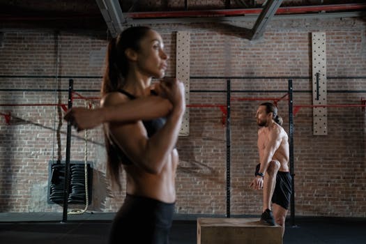 Two athletes warming up in an industrial-style gym, preparing for an intense workout session.