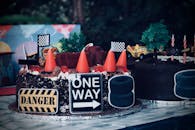 这款以赛车为主题的生日蛋糕特色是玩具车和标志，非常适合庆祝活动