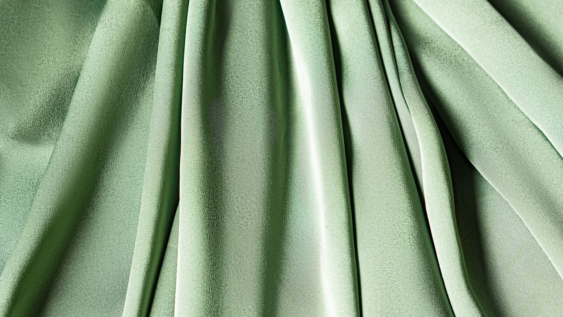 什麼是褶比?褶比會讓窗簾貴多少 Close-up of green fabric with a textured and pleated design, ideal for fashion or design concepts.