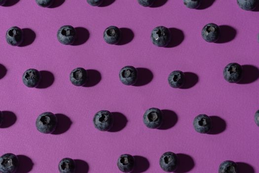 Fresh blueberries arranged in a pattern on a vibrant purple background. Perfect for food and health themes.