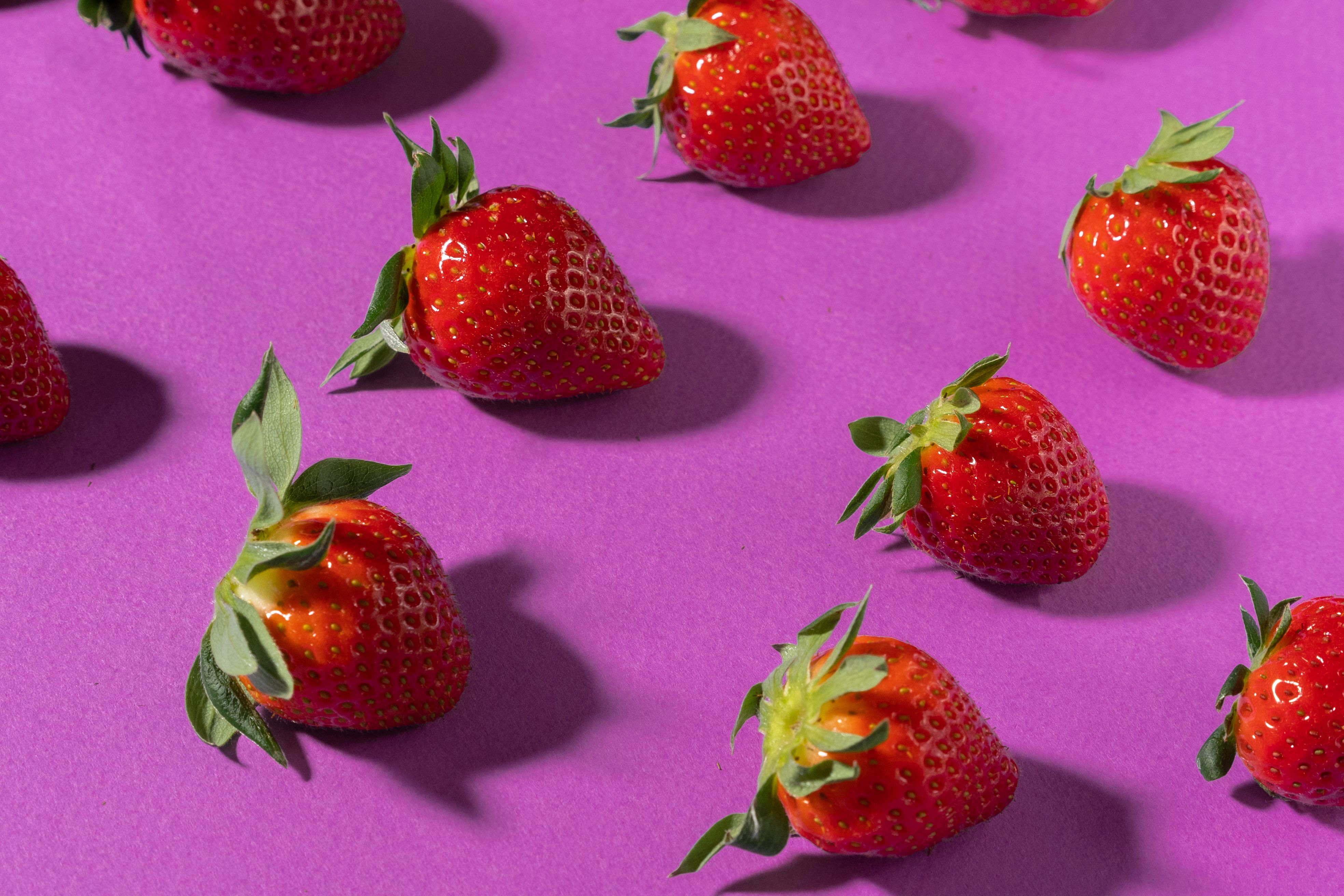 Bright and fresh strawberries arranged over a purple background. Perfect for health and nutrition themes.
