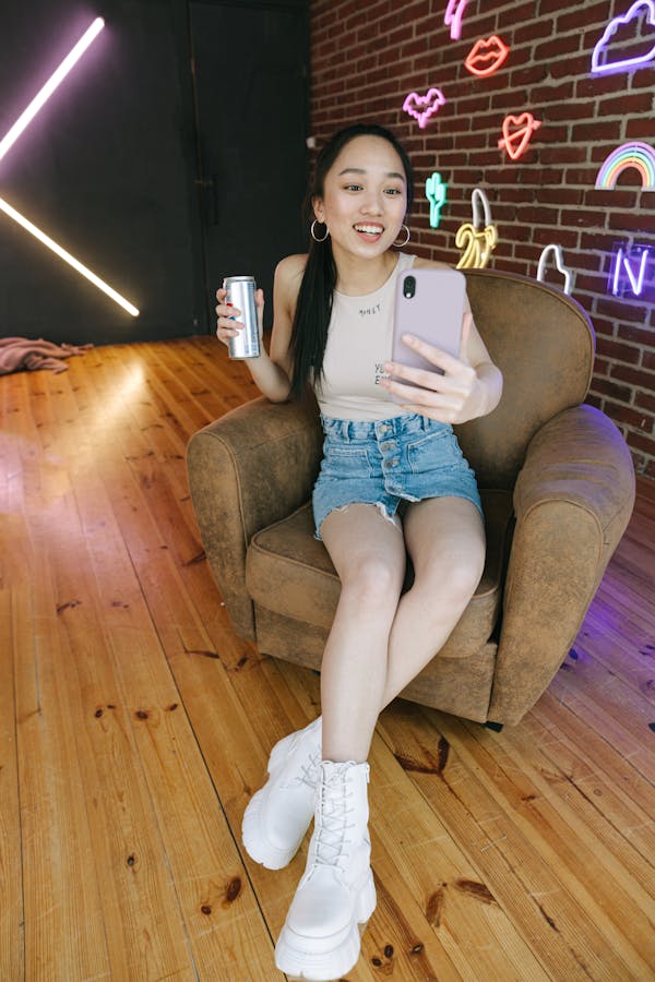 A Woman Sitting on the Chair while Holding Her Mobile Phone