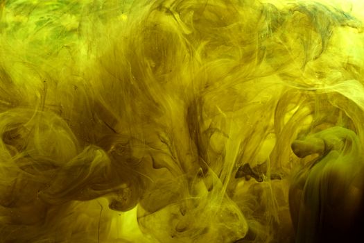 Dynamic abstract image of yellow ink swirling in water, creating a textured, artistic pattern.