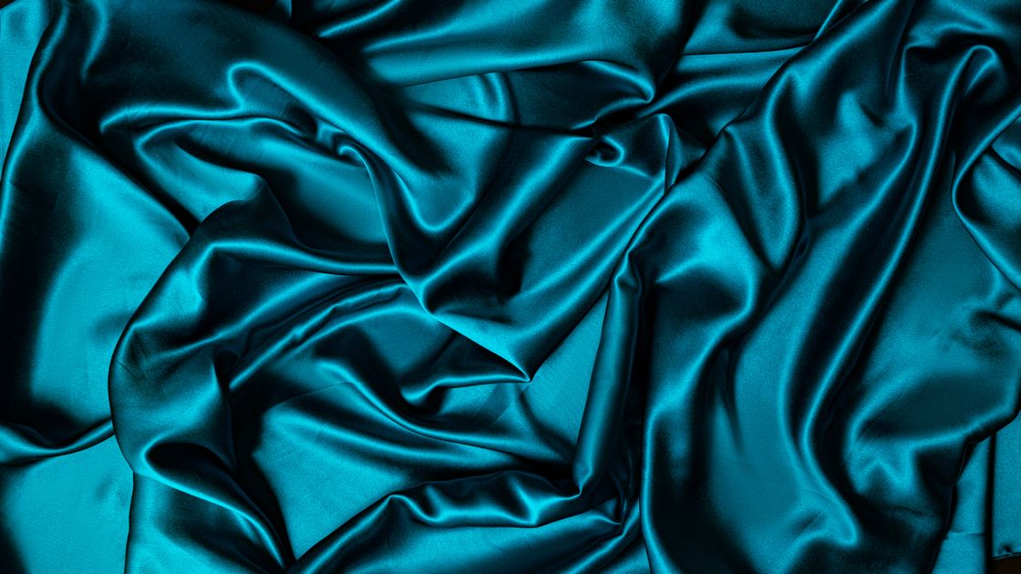 Satin xanh ngọc xếp nếp cho thấy ánh sáng phản chiếu trên bề mặt