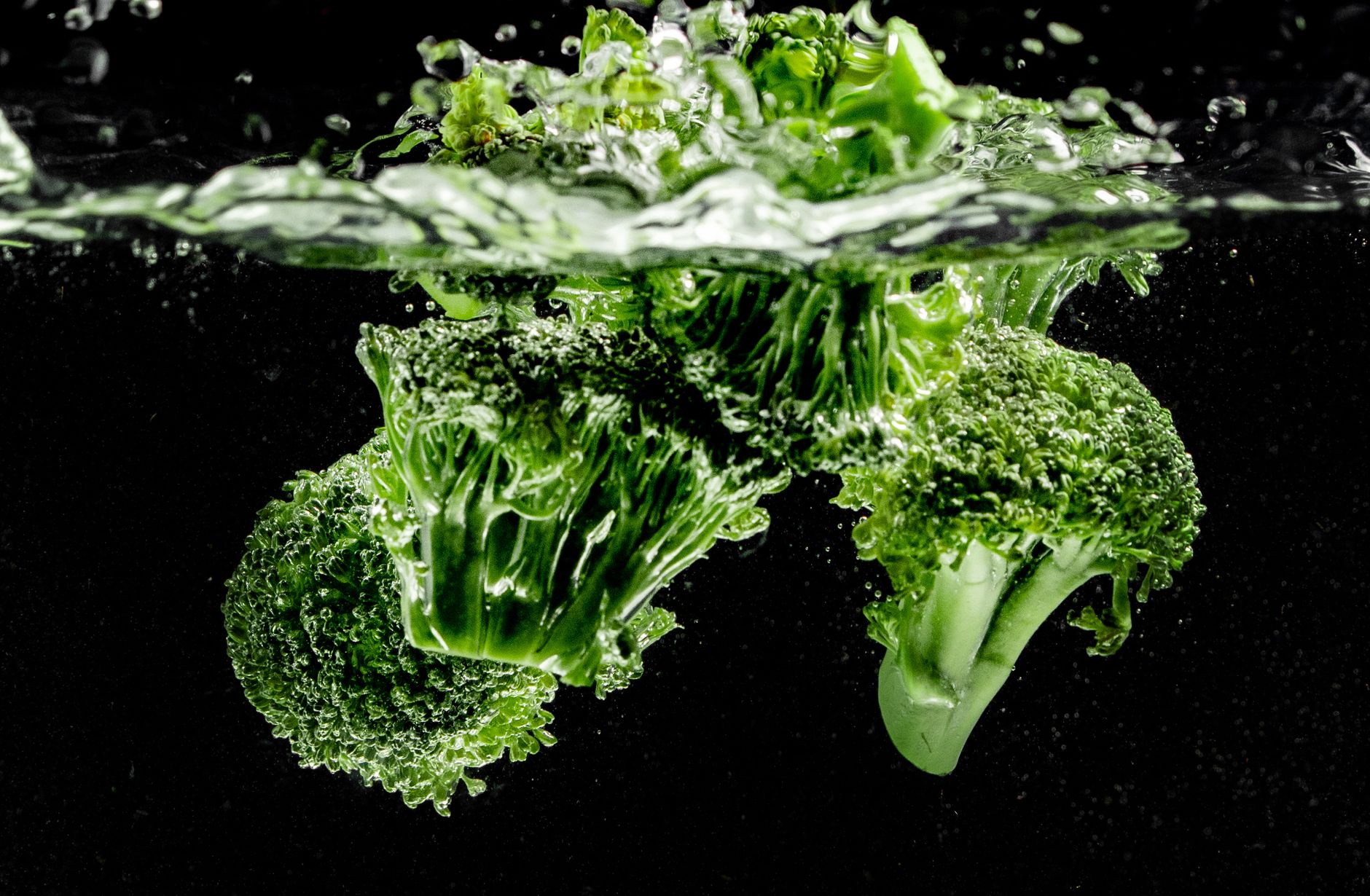 Vibrant broccoli submerged in water showcasing bubbles and texture, captured close-up.