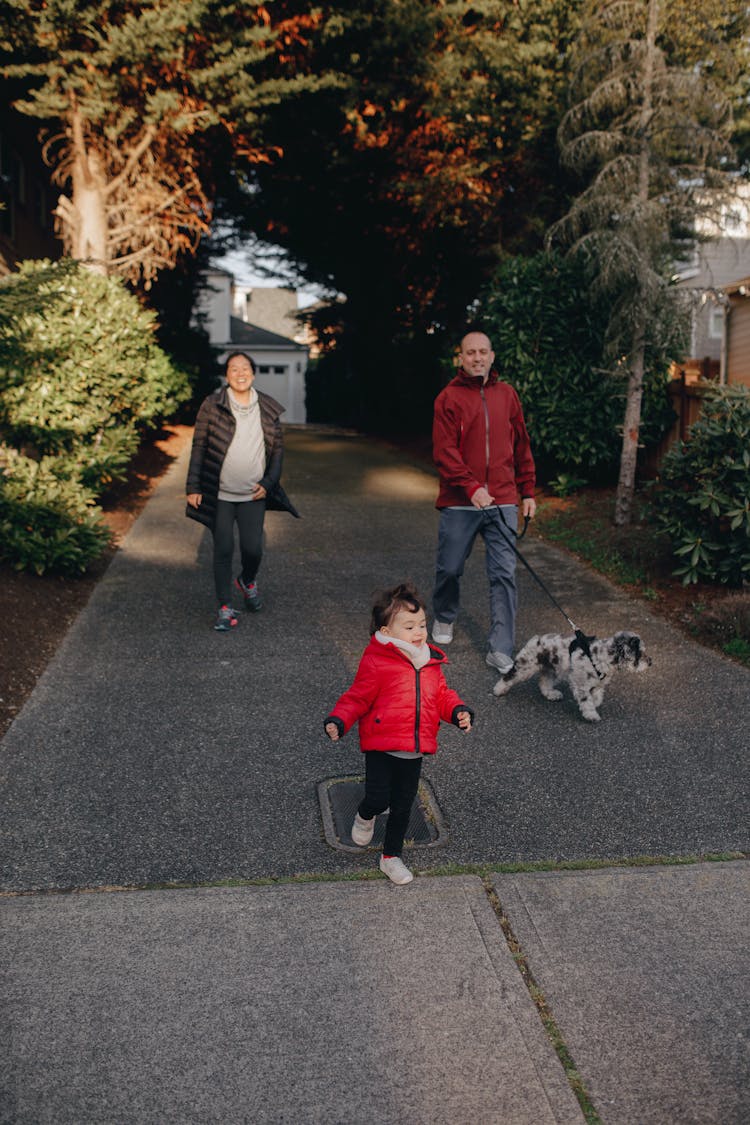 A Family Talking A Walk Outdoors With Their Dog