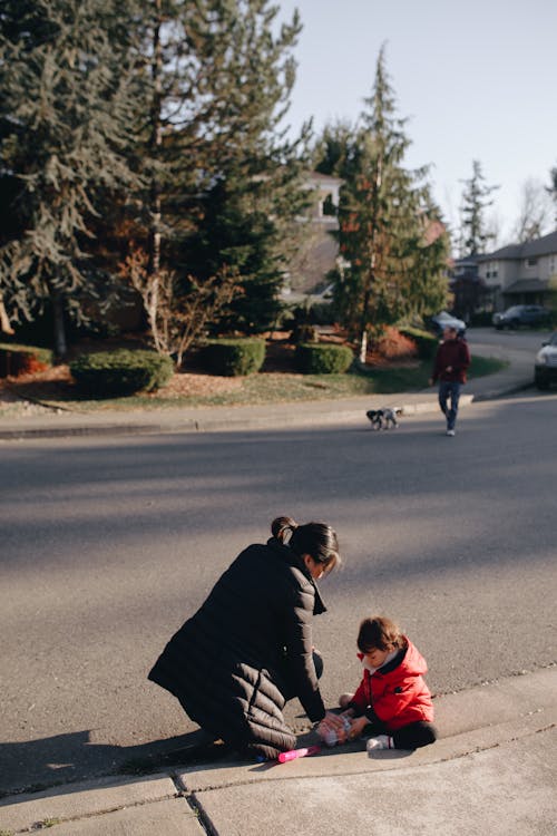 Woman Sitting By The Sidewalk With Her Child