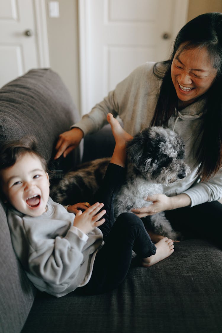 Happy Mother And Child Playing With Their Pet Dog