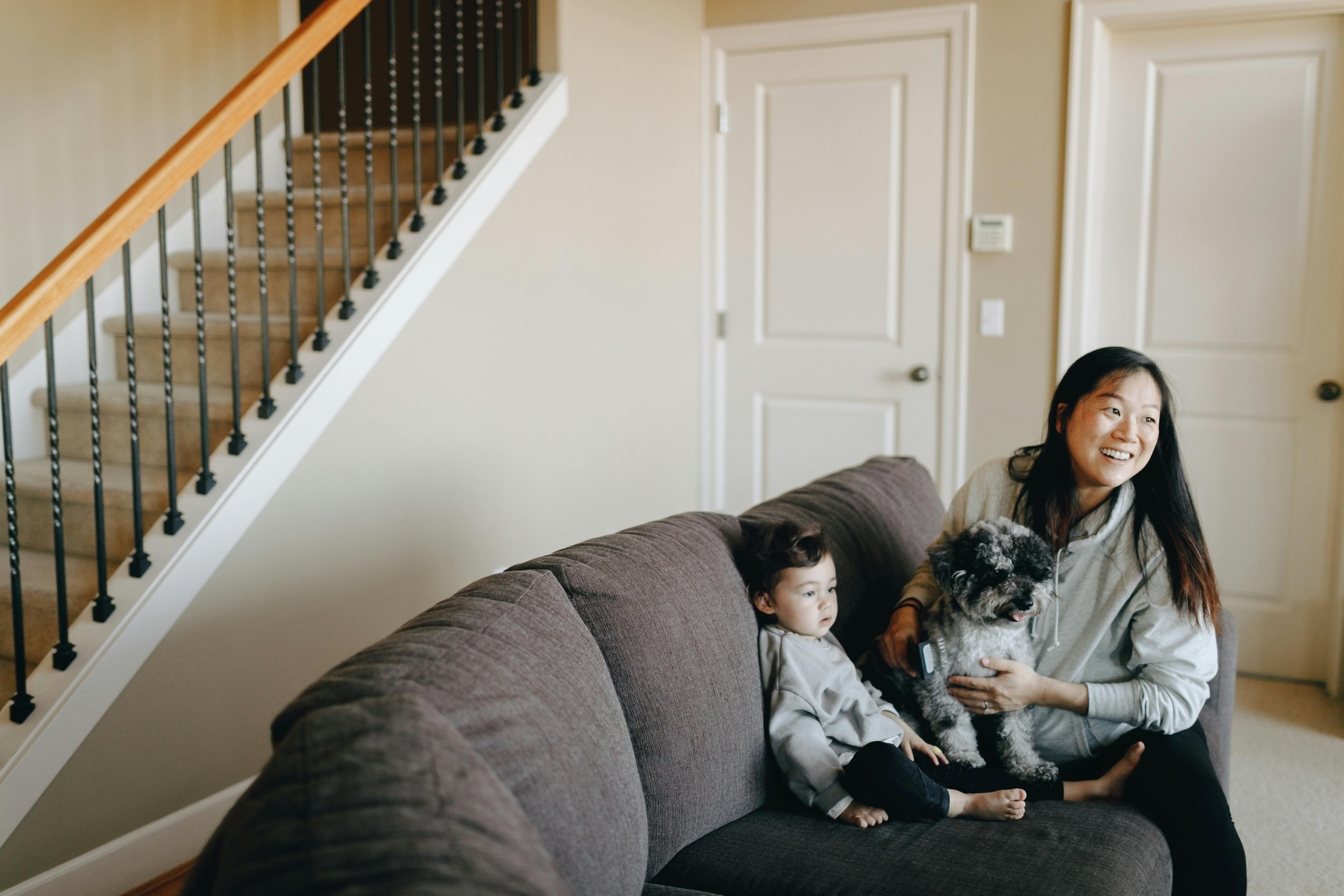 mother and child sitting on gray sofa with their dog