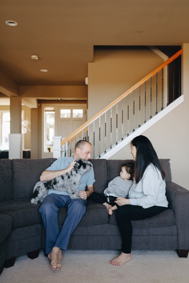 Family Sitting On Gray Sofa With Their Pet Dog