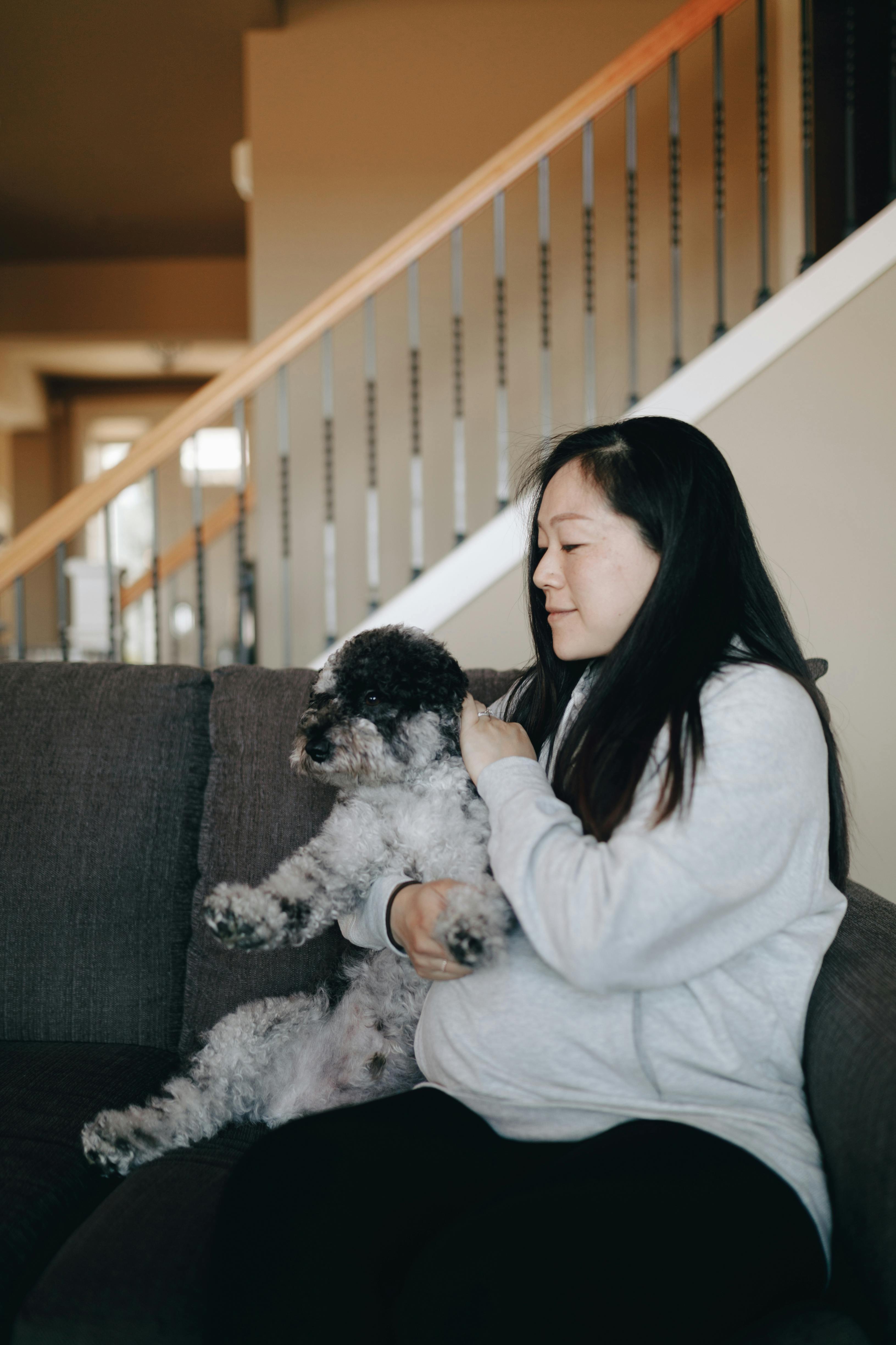 woman sitting on gray sofa with her pet dog