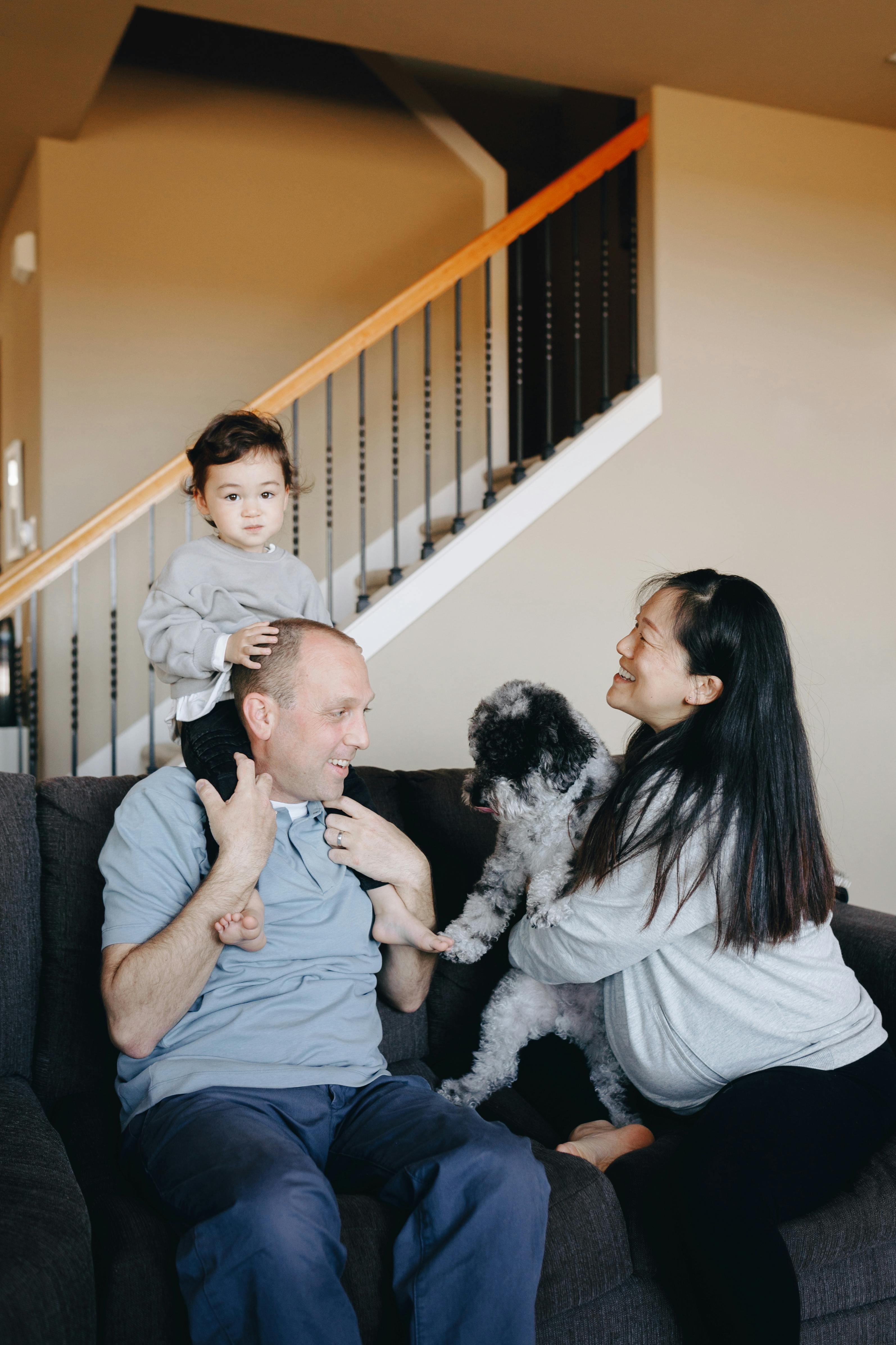 a happy family sitting on gray sofa with their dog