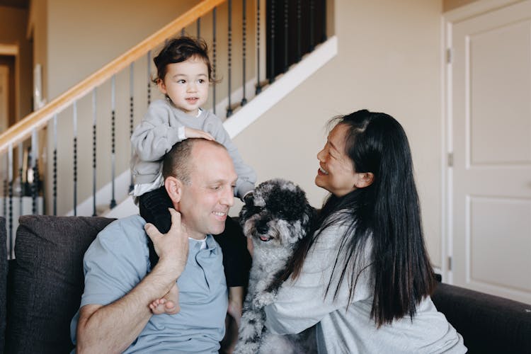 Family Sitting On Gray Sofa With Their Pet Dog