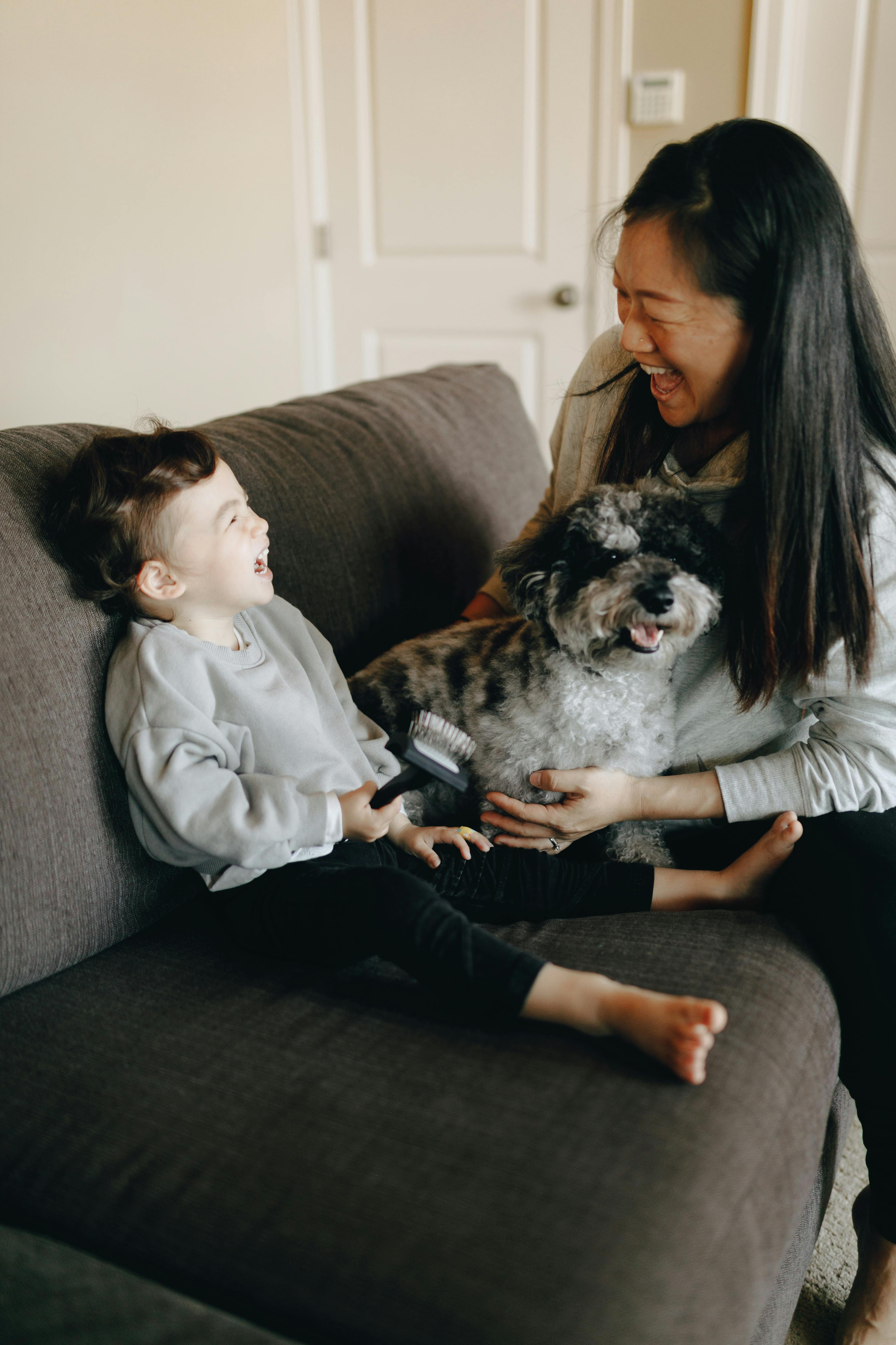 happy mother and child sitting on sofa with their pet dog