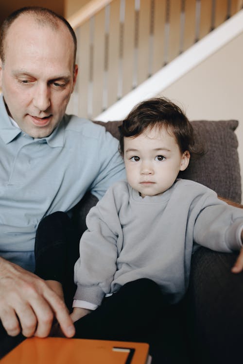 Father Sitting On Gray Sofa With His Child