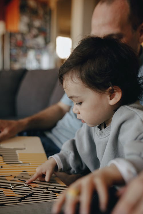 A Child Playing Beside Her Father