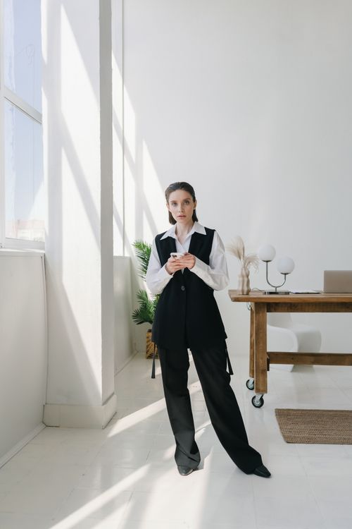Free A stylish businesswoman in a modern office setting using a smartphone. Stock Photo
