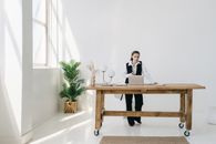 Woman in Black Vest Standing by the Brown Wooden Table